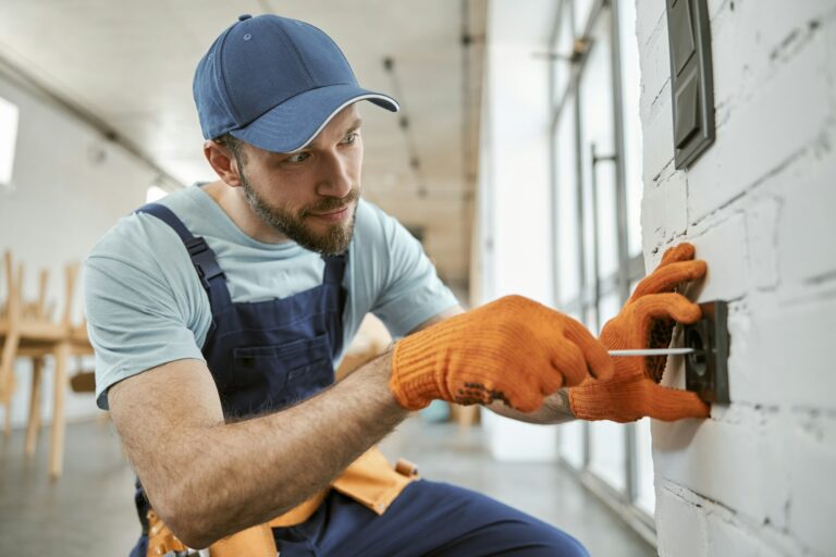 Bearded man fixing electrical wall socket with screwdriver.jpg