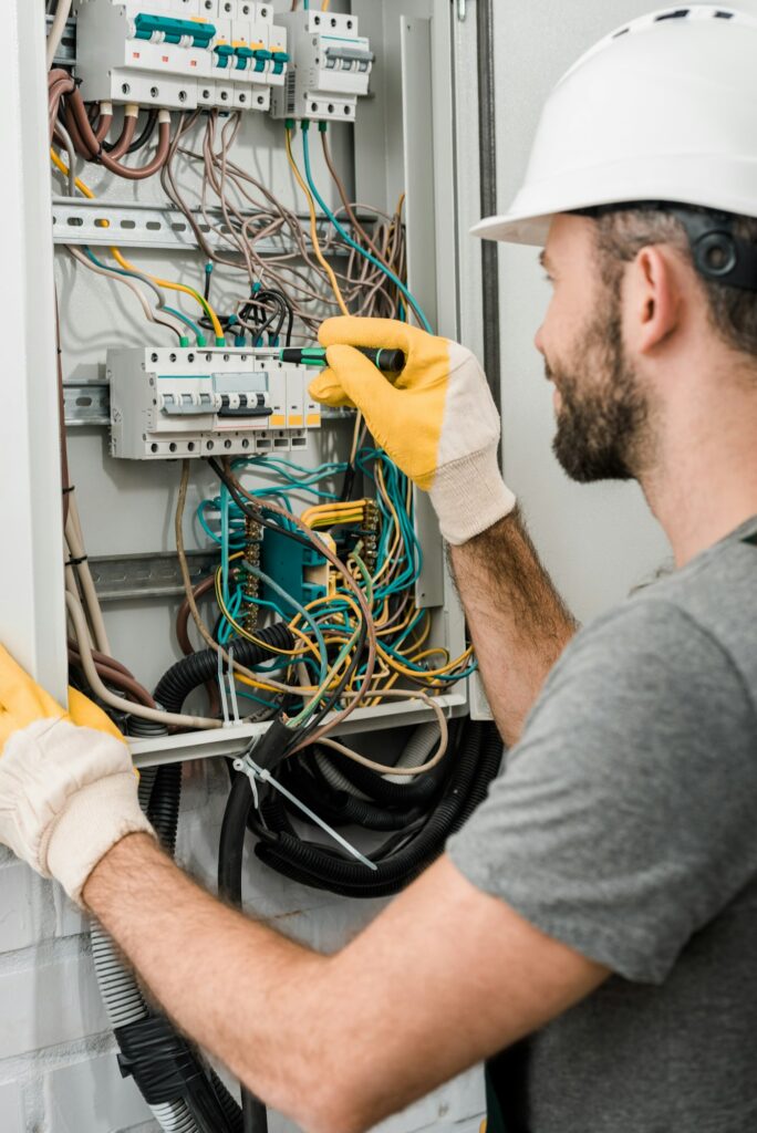 Side view of electrician repairing electrical box and using screwdriver in corridor.jpg